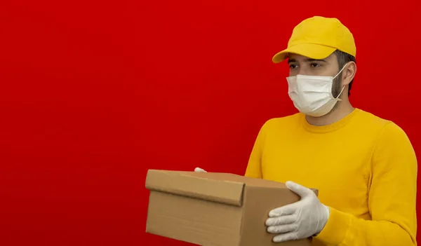 Karton kutuları tıbbi lastik eldiven ve maskeyle taşıyan teslimatçı. kopyalama alanı. Hızlı ve ücretsiz teslimat. İnternetten alışveriş ve ekspres teslimat. Karantina