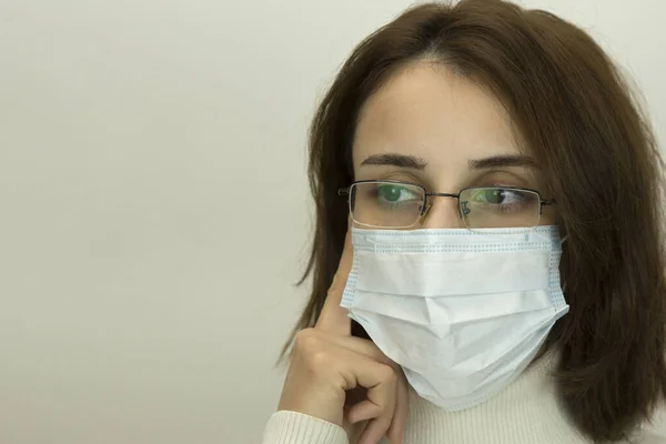 Young woman in glasses and a medical mask is thinking