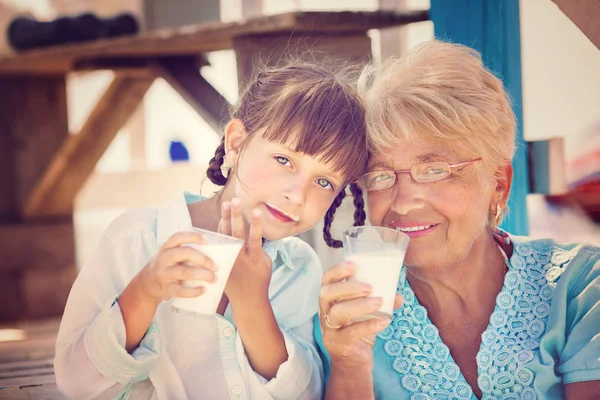 Grand-mère avec petite-fille boire du lait à l'extérieur — Photo