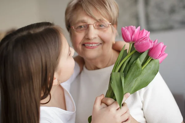 Március Női Nap Unokája Üdvözli Nagymamáját Ölelkezik Virágot — Stock Fotó
