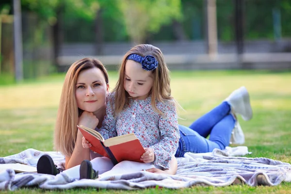 小さな女の子とともにお母さん読書面白い本屋外 — ストック写真