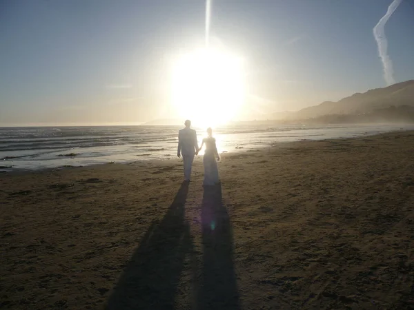 Just married couple walking into the sunset at Pismo Beach, California