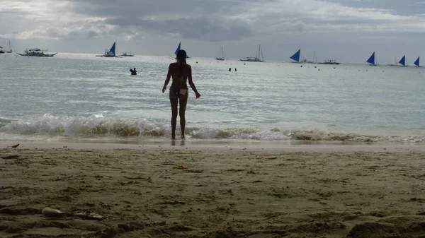 ビーチで船を見ている若い女性は — ストック写真