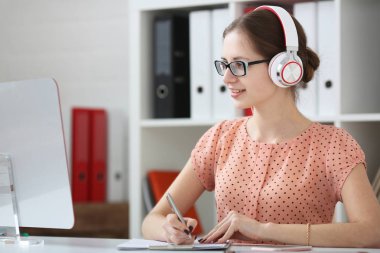 Kız öğrencinin öğrenme ve müzik kulaklık ile. Elini ve ekrana bakarak kolu tutun