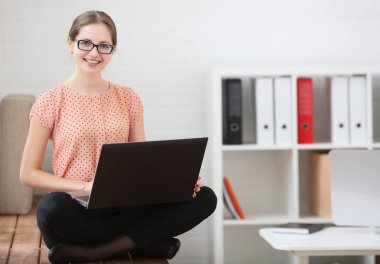 Lotus pozisyonda oturan bir dizüstü bilgisayar kullanarak okuyan kız öğrenci