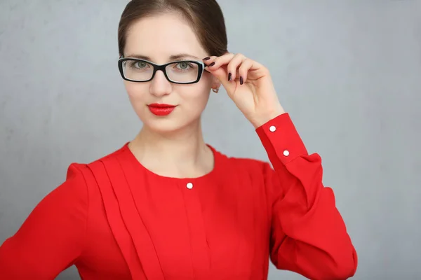 Модна ділова жінка з червоною сорочкою і портретом окулярів, тримаючи окуляри в руці — стокове фото