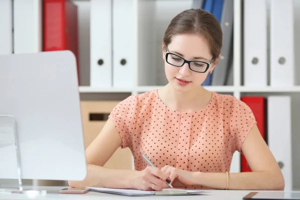 Vrouw in een kantoor neemt notities in een dagboek — Stockfoto