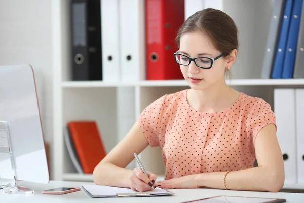 Vrouw in een kantoor neemt notities in een dagboek — Stockfoto