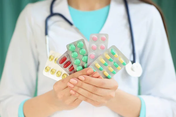 Une femme médecin tient une assiette avec des pilules dans les mains. Avec représentant — Photo