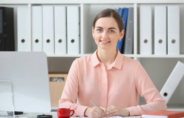 İş kadını portresi. O masa ve kameraya bakıyor ve elinde kalem tutan bir ofiste oturmuş