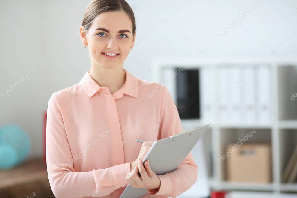 Portrait of business woman looking at the camera holding a folder in her hands and smiling