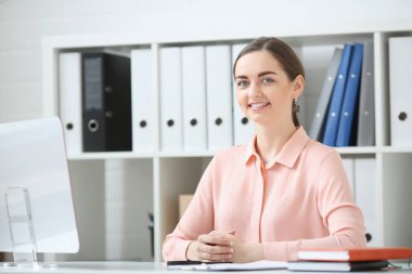 İş kadını portresi. O masa ve kameraya bakıyor ve elinde kalem tutan bir ofiste oturmuş
