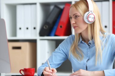 Sarışın kız öğrenci müzik ve öğrenme kulaklıklarla. Elini ve laptop monitör seyir kolu tutun