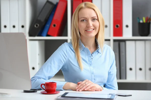 Zakenvrouw zit in een kantoor op een bureau glimlachen en kijken naar de camera — Stockfoto