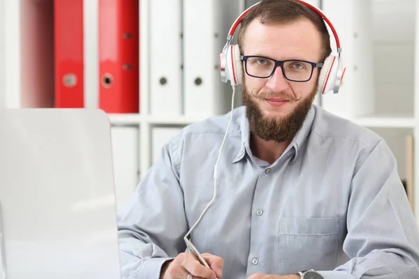 Bir adam kulaklık müzik dinliyor ve online öğrenir. Not bir not defterinde yapar ve kameraya benziyor