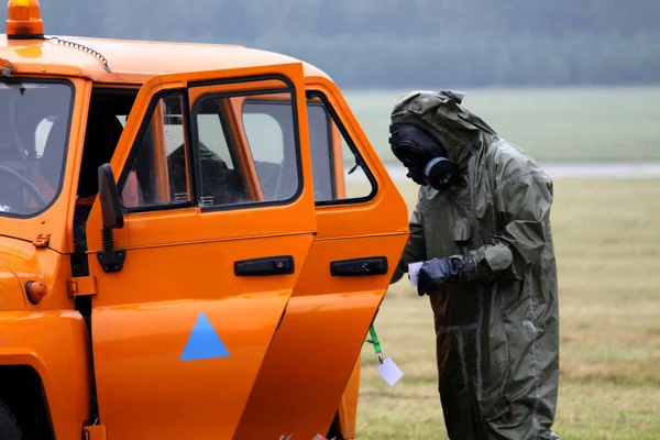 Man met gasmasker en veiligheidsjurk naast oranje auto — Stockfoto