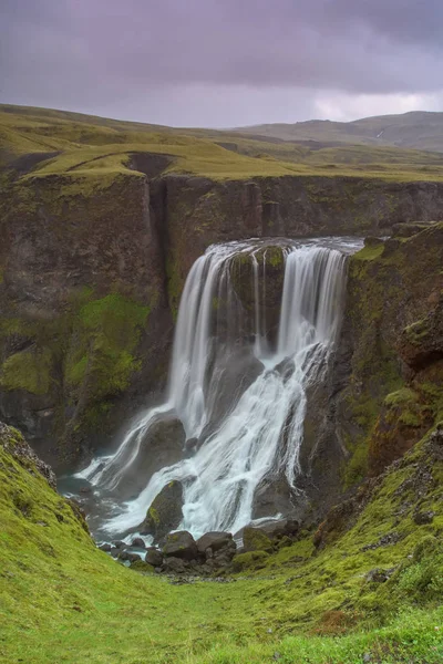 雨のすぐ後に素晴らしい滝Fagrifoss アイスランドの滝 美しい渓谷の絵のような滝 手前は緑の植生のある石や岩 空は暗い — ストック写真