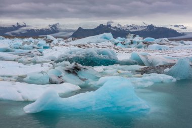 Jokulsarlon, İzlanda 'nın güneydoğusunda büyük bir buzul gölüdür. Yüzen buz, zarif bir lagünün sessiz yüzeyinde yüzer. Dramatik bir günbatımı gökyüzü yüzeye yansımaktadır.
