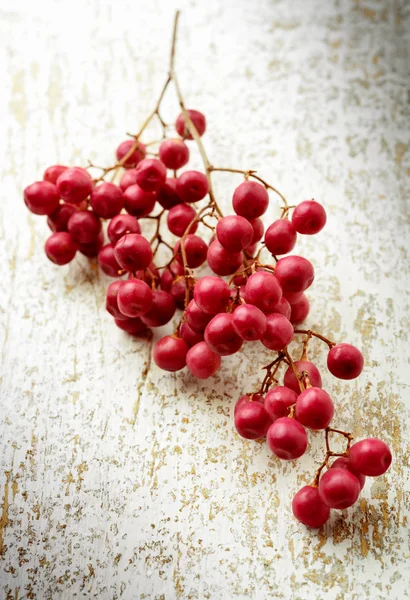 Cluster of pink peppercorns on aged wood — Stock Photo, Image