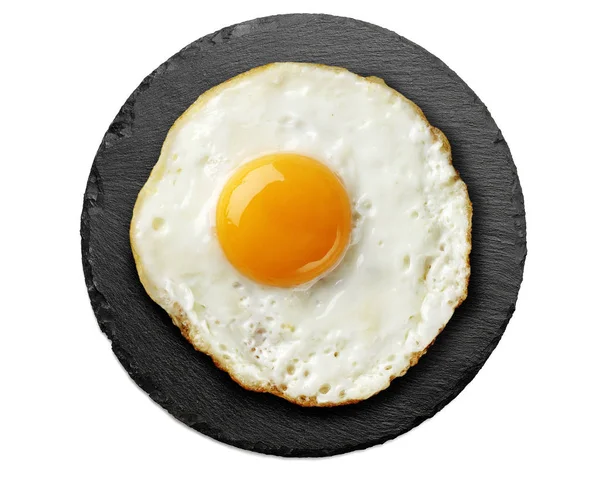 Fried egg on round black slate — Stock Photo, Image