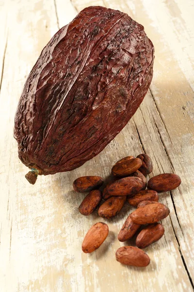 Cocoa beans and pod on aged wood — Stock Photo, Image