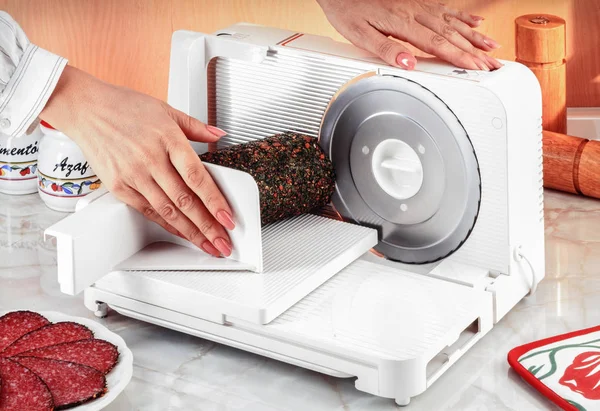 Electric slicer with hand slicing a salami — Stock Photo, Image