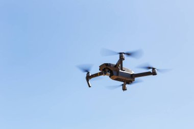 Unmanned aerial vehical with video camera hovers in the air. Thi clipart
