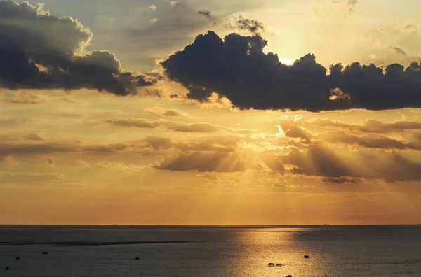 Sombra de luz solar por trás da nuvem escura antes do pôr do sol sobre o mar e s — Fotografia de Stock