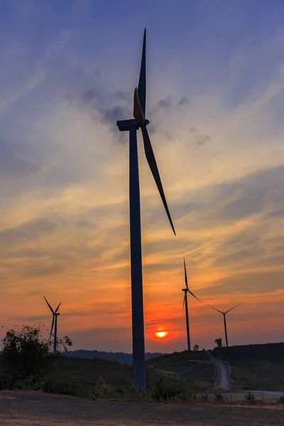 Silhouette wind turbine farm over moutain with orange sunset and — Stock Photo, Image