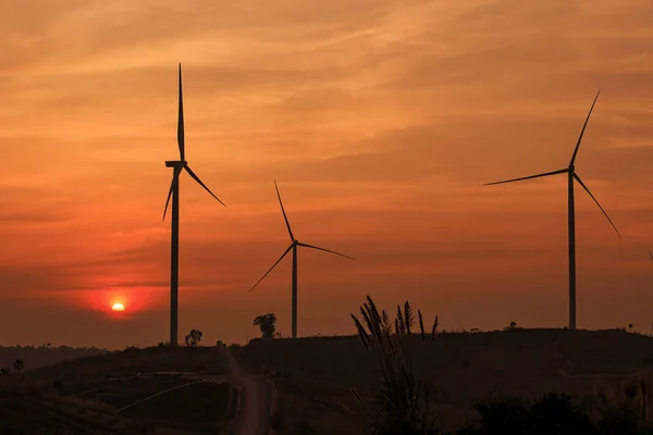 Silhouette parco eolico sopra la montagna con tramonto arancione e — Foto Stock