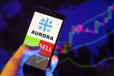 Yessentuki, Rusya - 27 Temmuz 2019: Akıllı telefon ekranında şirket logosu Aurora Cannabis Inc. (Acb), hisse senedi grafiğinin arka planında Buy ya da Satış 'ı gösteren bir tüccar eli
