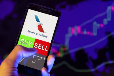 Yessentuki, Rusya - 27 Temmuz 2019: Akıllı telefon ekranında Amerikan Havayolları Grubu (Aal) logosu, hisse senedi grafiğinin arka planında Buy ya da Satış 'ı gösteren bir tüccar eli