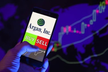 Yessentuki, Rusya - 27 Temmuz 2019: Akıllı telefon ekranında şirket logosu Argan, Inc. (Agx), hisse senedi grafiğinin arka planında Buy ya da Satış 'ı gösteren cep telefonu tüccarının eli