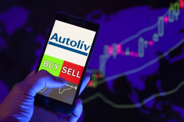 Yessentuki, Rusya - 27 Temmuz 2019: Akıllı telefon ekranında şirket logosu, hisse senedi grafiğinin arka planında Buy veya Satış gösteren bir tüccar eli.