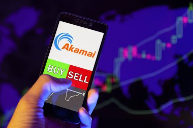 Yessentuki, Rusya - 27 Temmuz 2019: Akıllı telefon ekranında şirket logosu Akamai Technologies Inc., Buy or Sell 'in hisse senedi grafiğinin arka planında yer aldığını gösteren cep telefonu tüccarının eli