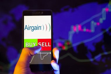 Yessentuki, Rusya - 25 Temmuz 2019: Akıllı telefon ekranında şirket logosu, hisse senedi grafiğinin arka planında Buy ya da Satış 'ı gösteren bir tüccar eli