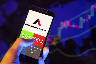 Yessentuki, Rusya - 25 Temmuz 2019: Akıllı telefon ekranında Amerikan Kulesi logosu, hisse senedi grafiğinin arka planında Buy ya da sell 'i gösteren bir tüccar eli