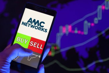 Yessentuki, Rusya - 25 Temmuz 2019: Akıllı telefon ekranında şirket logosu Amc Networks Inc., Buy or Ssell 'in hisse senedi grafiğinin arka planında yer aldığını gösteren cep telefonu tutan tüccarın eli