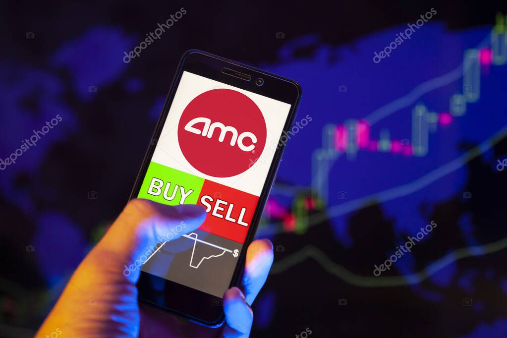 YESSENTUKI, RUSSIA - July 25, 2019: Company logo AMC ENTERTAINMENT HOLDINGS Inc on smartphone screen, hand of trader holding mobile phone showing BUY or SELL on background of stock chart