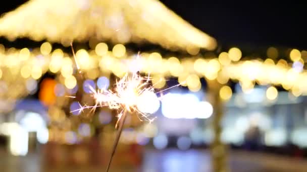 Burning Sparkler da vicino sullo sfondo delle luci di Natale sulla strada — Video Stock