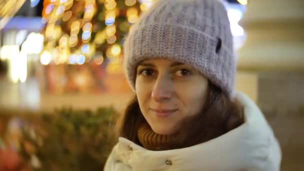 Retrato de bela jovem no inverno em um fundo de luzes de Natal ao ar livre — Vídeo de Stock