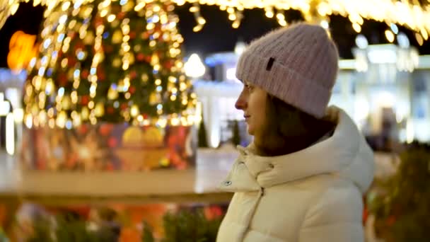Ritratto di bella giovane donna in inverno su sfondo di luci natalizie — Video Stock