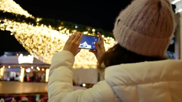 Giovane donna in giacca assume il telefono Albero di Natale all'aperto — Video Stock