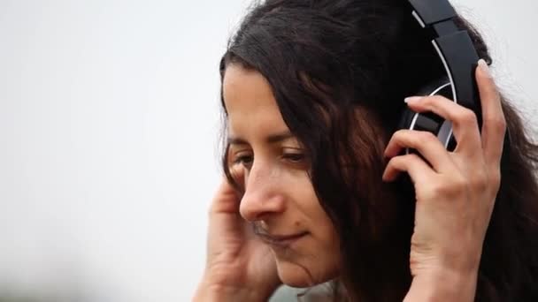 Closeup of young woman wearing headphones and listening to music — Stock Video