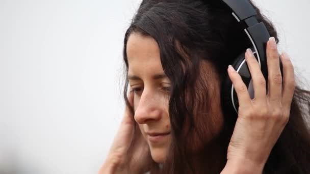 Primer plano de la joven mujer que usa auriculares y escucha música — Vídeos de Stock