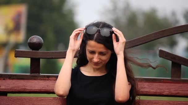 Retrato de mujer joven, ella en el parque pone gafas de sol — Vídeo de stock