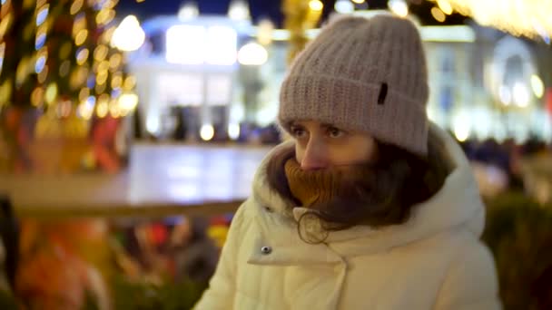 Bella giovane donna congelato e riscaldando le mani sull'albero di Natale all'aperto — Video Stock