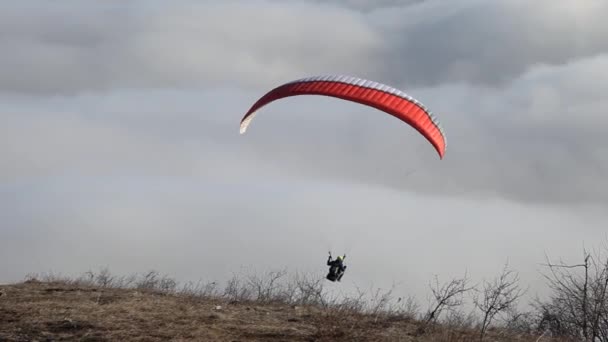 山と雲の上を飛ぶパラグライダー — ストック動画
