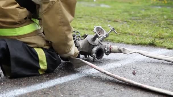 Primo piano di un vigile del fuoco si attacca ai tubi antincendio e svita le valvole — Video Stock