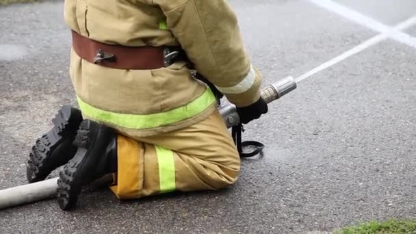 Nahaufnahme eines sitzenden Feuerwehrmannes löscht das Feuer mit Feuerwehrschlauch — Stockvideo